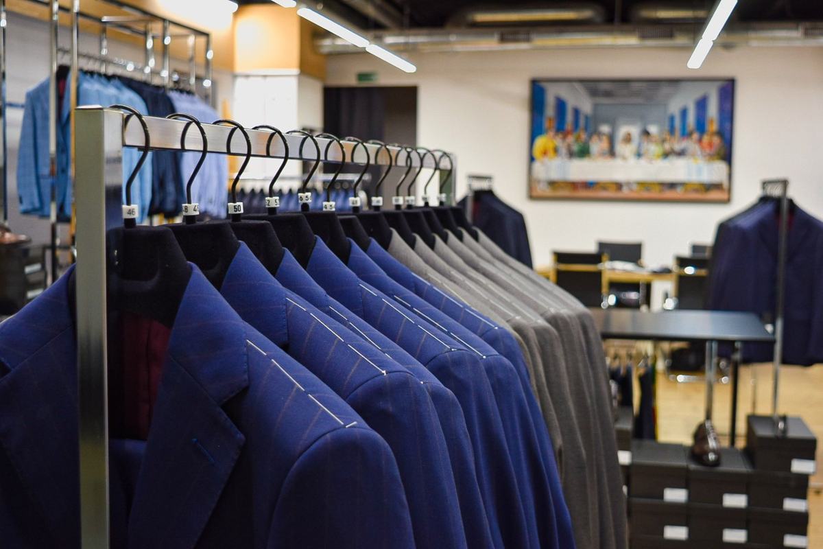 Un portant de vestes bleu roi, fils de bâti blancs sur les épaules et tailles chiffrées aux cintres