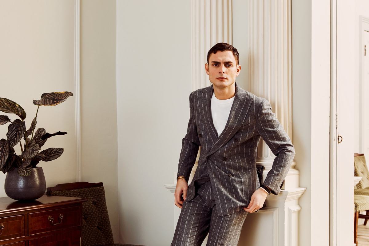 Costume croisé gris à rayures craie, porté avec un tee-shirt blanc dans un intérieur clair