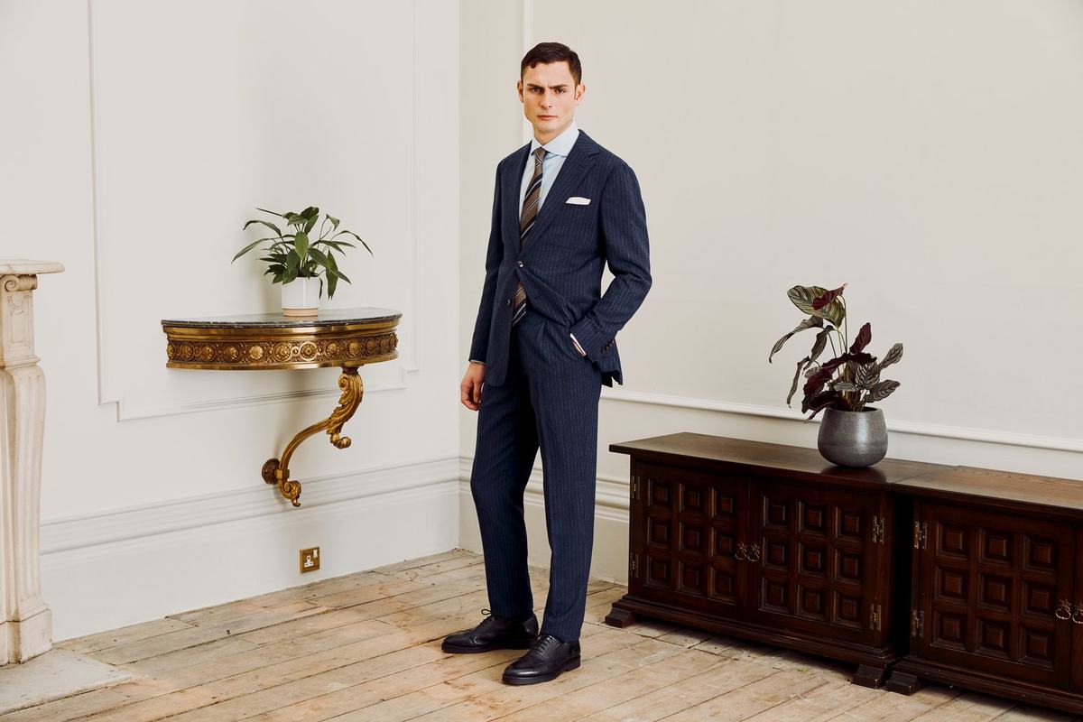 Costume deux-pièces bleu nuit à rayures craie, porté avec chemise bleu clair, cravate et pochette blanche