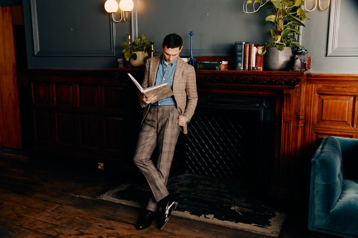 Un homme en veste pied-de-poule et pantalon prince-de-galles, chaussé de mocassins noirs