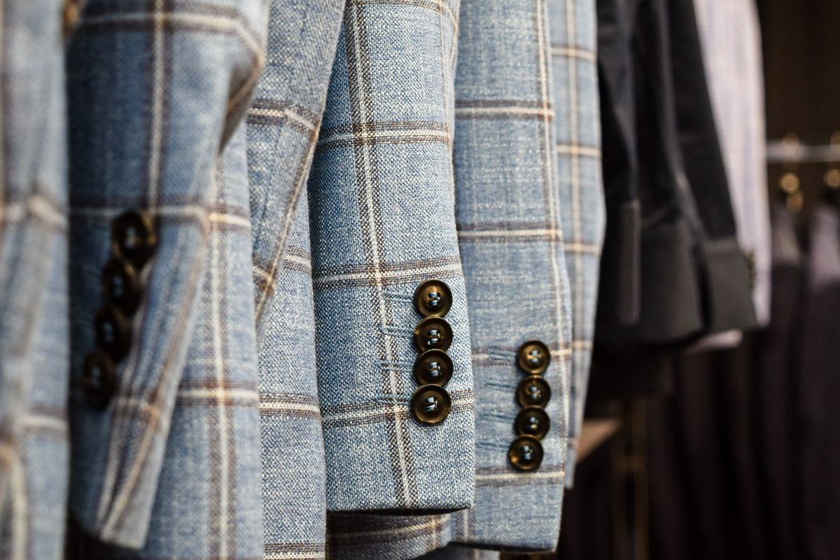 Manches de vestes bleu clair à grands carreaux, quatre boutons brun foncé alignés au poignet